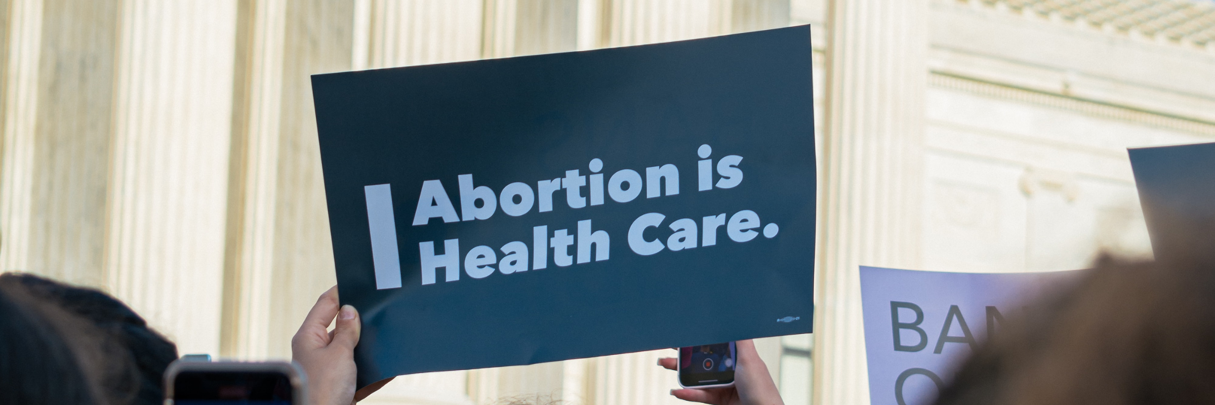 Person holding sign in front of supreme court that says "Abortion is Health Care."
